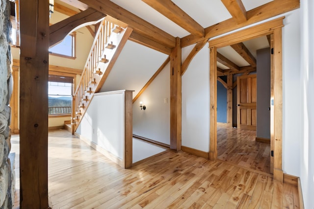 interior space with beam ceiling and light hardwood / wood-style flooring