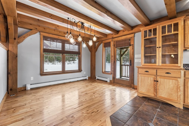 unfurnished dining area with a healthy amount of sunlight, an inviting chandelier, and a baseboard radiator