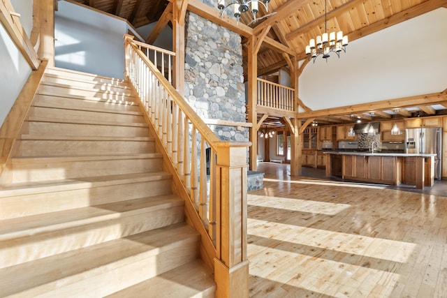 staircase featuring wood ceiling, beamed ceiling, high vaulted ceiling, a notable chandelier, and hardwood / wood-style flooring