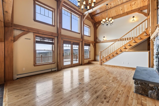 unfurnished living room featuring wood ceiling, a baseboard heating unit, a notable chandelier, light wood-type flooring, and beam ceiling