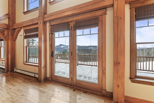 doorway to outside with baseboard heating, a mountain view, and light hardwood / wood-style flooring