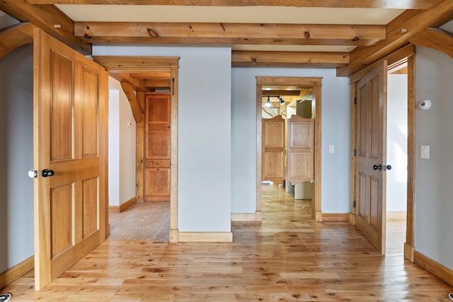 corridor featuring light wood-type flooring and beamed ceiling