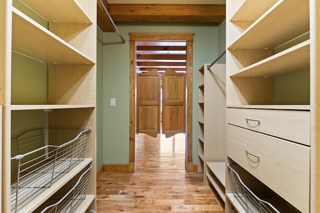 spacious closet with beam ceiling and light wood-type flooring