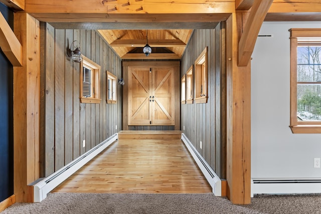 interior space featuring carpet, a baseboard heating unit, and wood walls