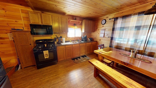 kitchen with sink, wooden ceiling, light wood-type flooring, and black appliances