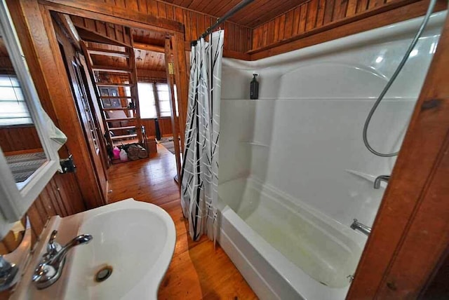 bathroom with shower / tub combo with curtain, sink, wood ceiling, and wood walls