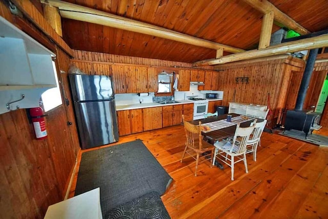 kitchen with stainless steel appliances, wood-type flooring, and wood walls