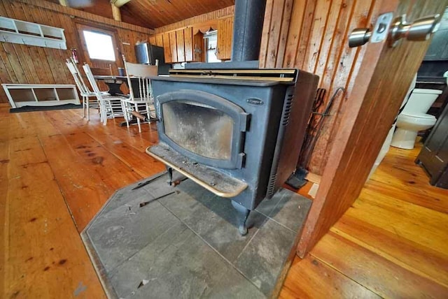 interior details with a wood stove, hardwood / wood-style floors, wood ceiling, and wood walls