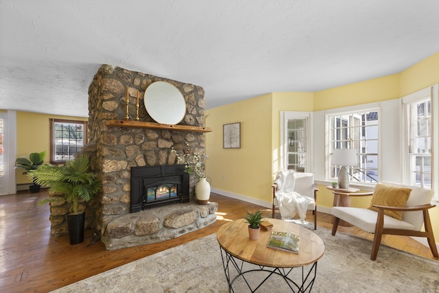 living room with hardwood / wood-style flooring, a baseboard heating unit, a textured ceiling, and a fireplace