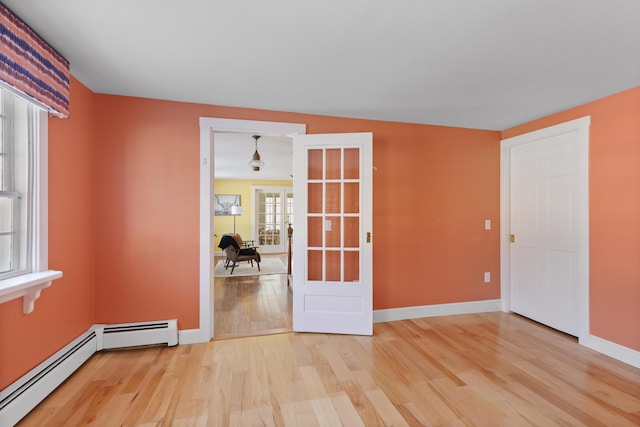 empty room with baseboard heating and light wood-type flooring