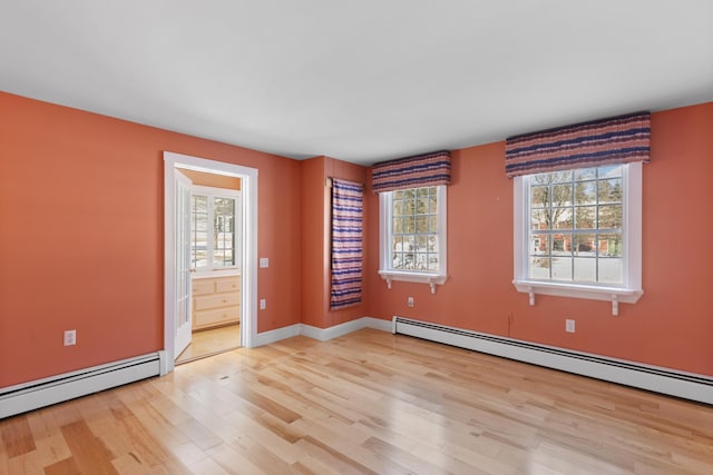 spare room with baseboard heating and light hardwood / wood-style flooring