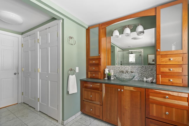 bathroom with tile patterned floors, vanity, an enclosed shower, and decorative backsplash