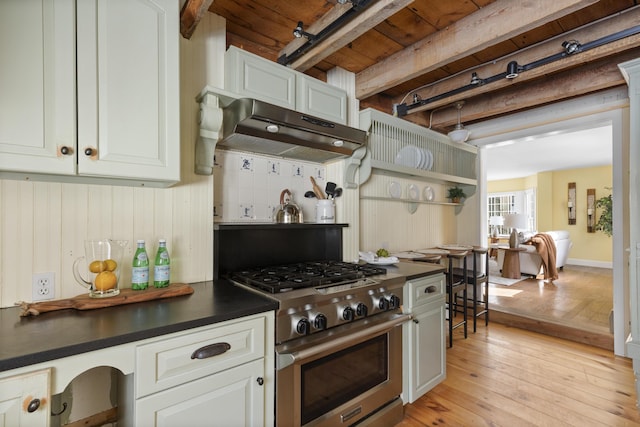 kitchen featuring white cabinetry, light hardwood / wood-style floors, stainless steel stove, and beamed ceiling