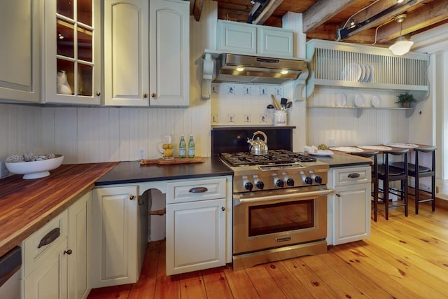 kitchen with butcher block countertops, appliances with stainless steel finishes, range hood, light hardwood / wood-style floors, and decorative backsplash