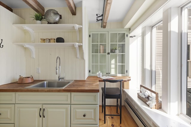 kitchen featuring butcher block counters, sink, light hardwood / wood-style flooring, and a baseboard heating unit