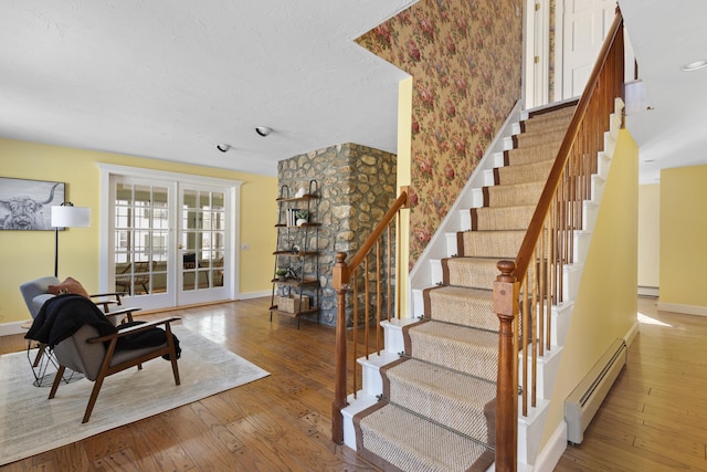 interior space featuring hardwood / wood-style flooring, a textured ceiling, baseboard heating, and french doors