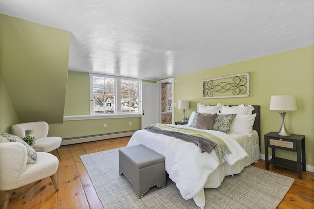 bedroom with a baseboard radiator, wood-type flooring, and a textured ceiling