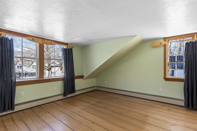 additional living space featuring vaulted ceiling, a textured ceiling, and light wood-type flooring