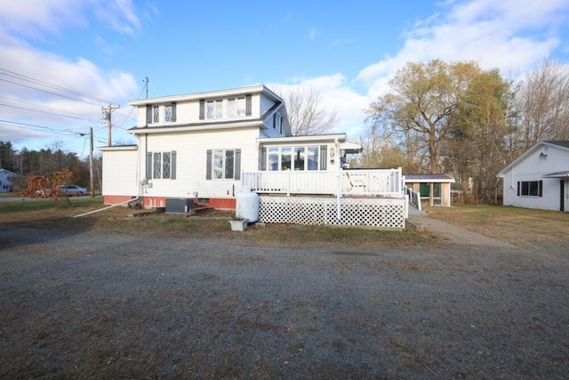 view of front of home with a deck, a carport, central AC, and a sunroom