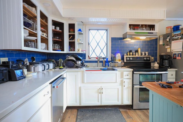 kitchen with open shelves, tasteful backsplash, appliances with stainless steel finishes, wood finished floors, and under cabinet range hood