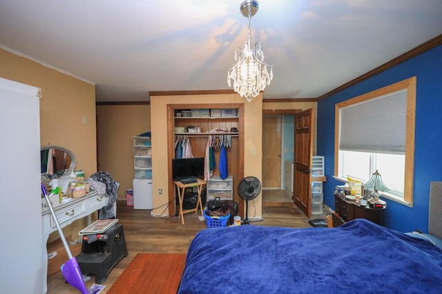 bedroom featuring a closet, crown molding, an inviting chandelier, and wood finished floors