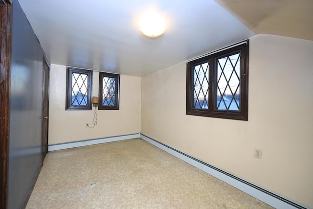 empty room with a wealth of natural light, baseboards, lofted ceiling, and baseboard heating