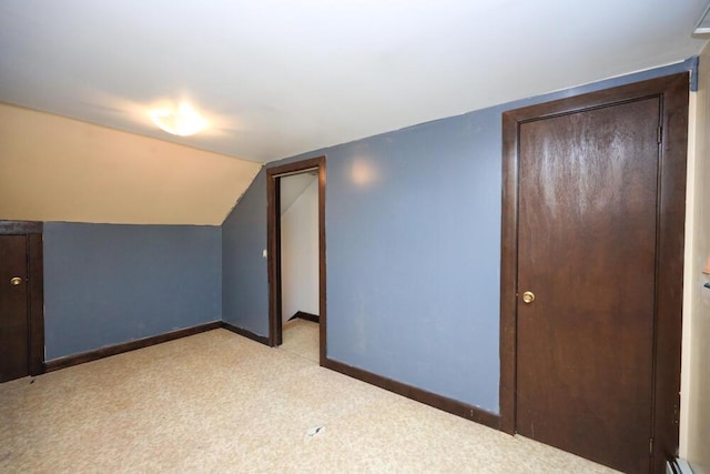 bonus room featuring lofted ceiling, light carpet, and baseboards