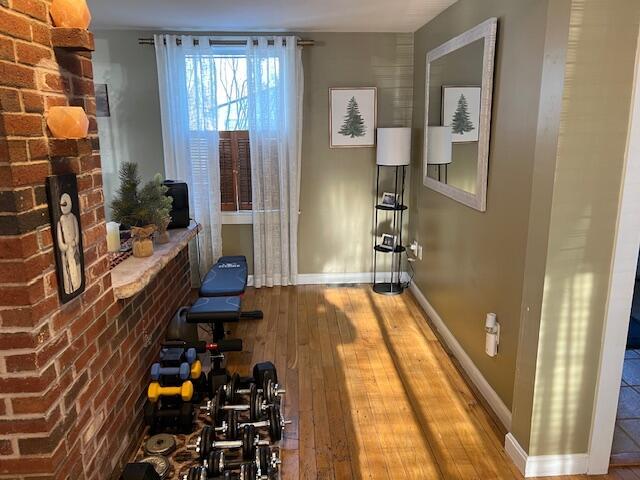 exercise room featuring brick wall and hardwood / wood-style floors