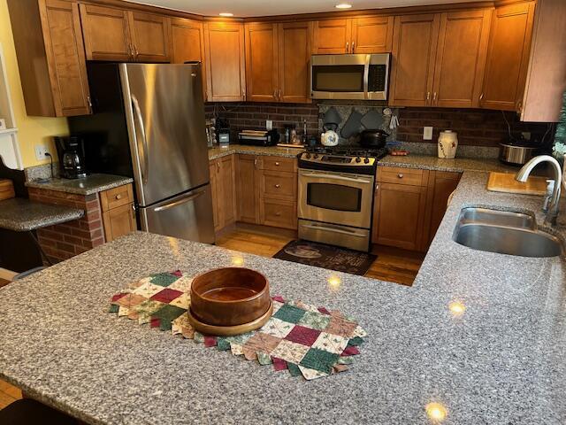 kitchen with light stone counters, stainless steel appliances, sink, and a breakfast bar area