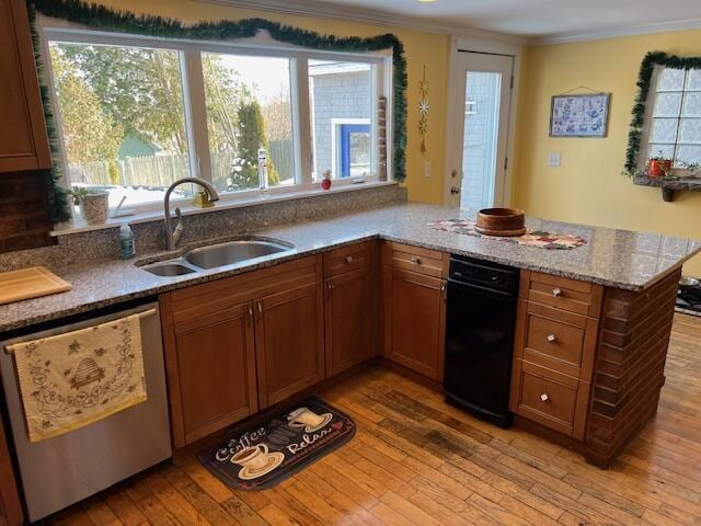 kitchen featuring sink, dishwashing machine, ornamental molding, kitchen peninsula, and light wood-type flooring