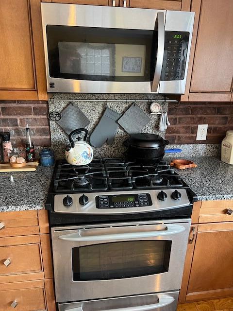 kitchen with backsplash, stainless steel appliances, and dark stone countertops