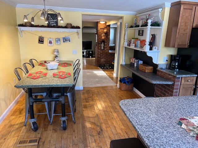 kitchen with crown molding, decorative light fixtures, a breakfast bar, and light hardwood / wood-style floors