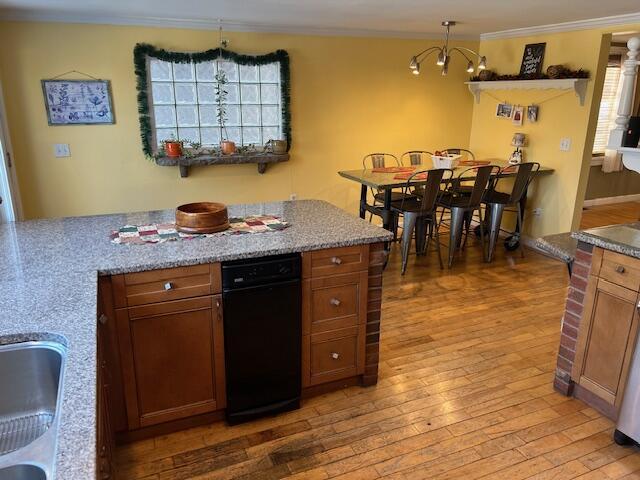 kitchen with pendant lighting, sink, hardwood / wood-style flooring, ornamental molding, and a chandelier