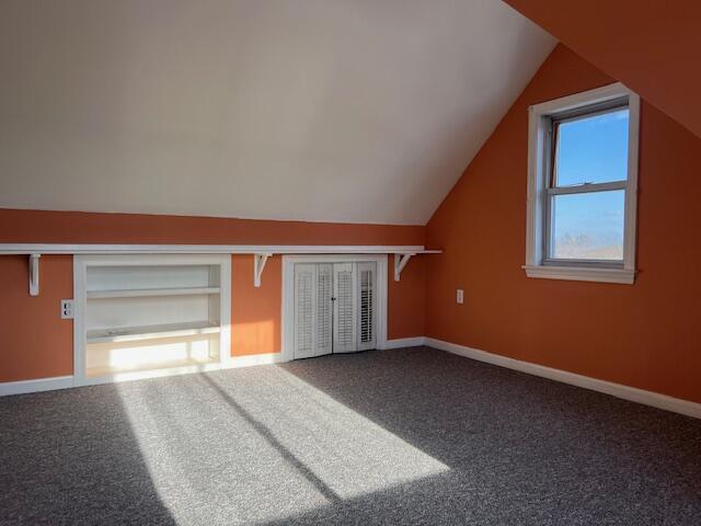 bonus room with vaulted ceiling and carpet