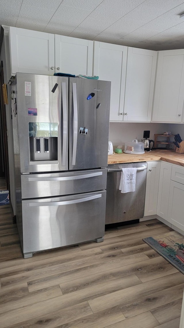 kitchen with white cabinetry, appliances with stainless steel finishes, butcher block counters, and light wood-type flooring