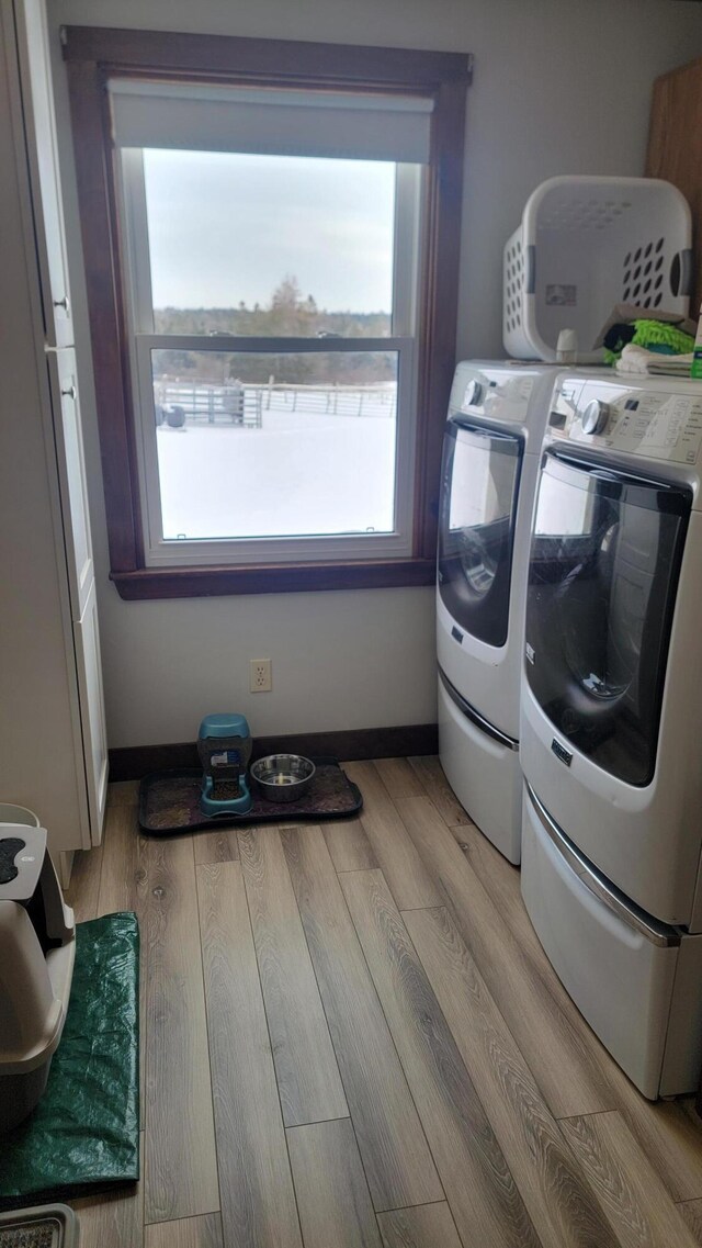 laundry area featuring washing machine and dryer and light hardwood / wood-style flooring