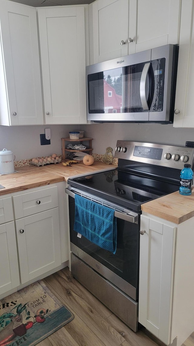 kitchen featuring white cabinets, appliances with stainless steel finishes, wooden counters, and light wood-type flooring