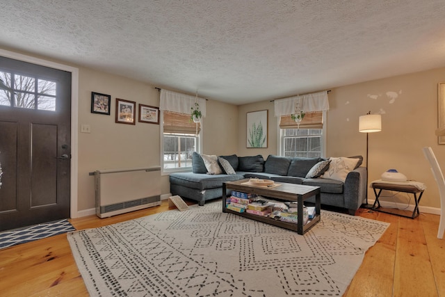 living room featuring radiator heating unit, a wealth of natural light, wood-type flooring, and a textured ceiling