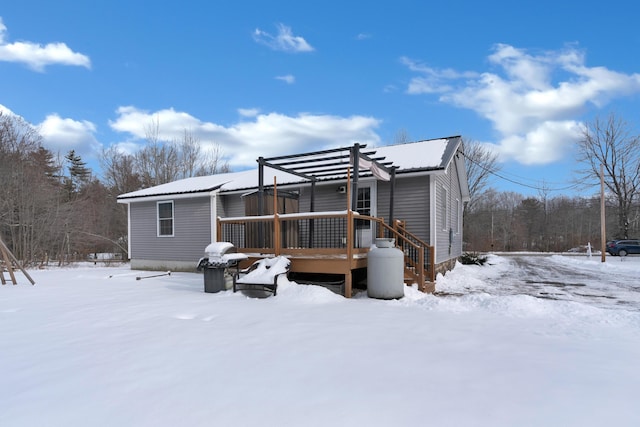 snow covered house featuring a wooden deck and a pergola