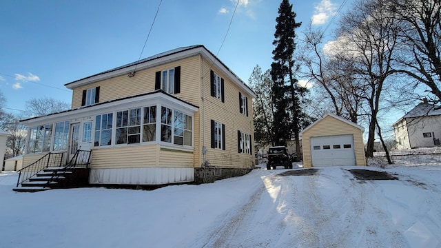 view of snow covered exterior featuring a garage and an outbuilding