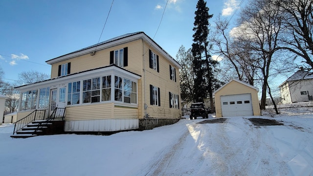 view of snow covered exterior featuring a garage and an outbuilding