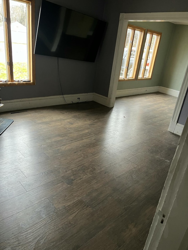 spare room with dark wood-style flooring and baseboards