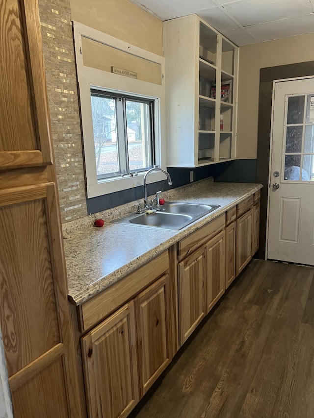 kitchen featuring brown cabinets, dark wood-type flooring, light countertops, and a sink