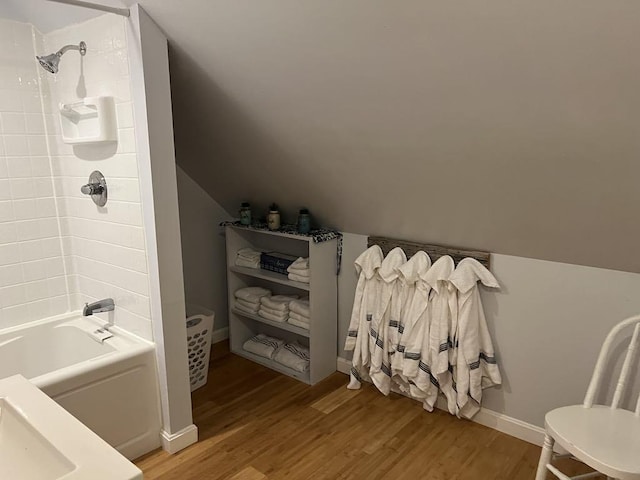 bathroom with tiled shower / bath combo, wood-type flooring, and lofted ceiling