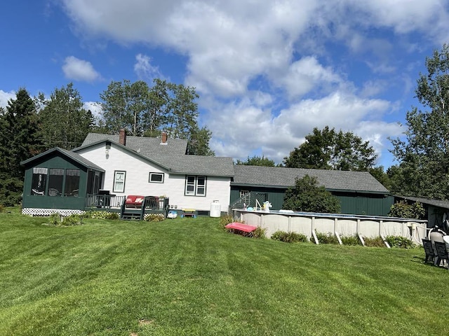 rear view of property with a pool side deck, a yard, and a sunroom