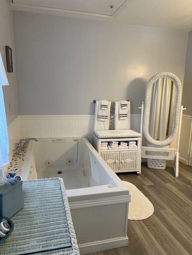 bathroom with a tub to relax in and hardwood / wood-style flooring