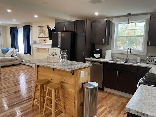 kitchen featuring a center island, sink, a kitchen breakfast bar, black fridge, and stainless steel dishwasher