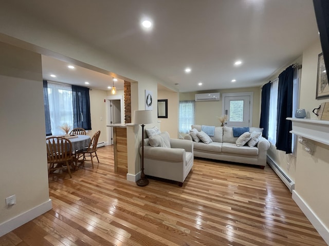 living room featuring a wall mounted AC, light hardwood / wood-style flooring, and a baseboard radiator