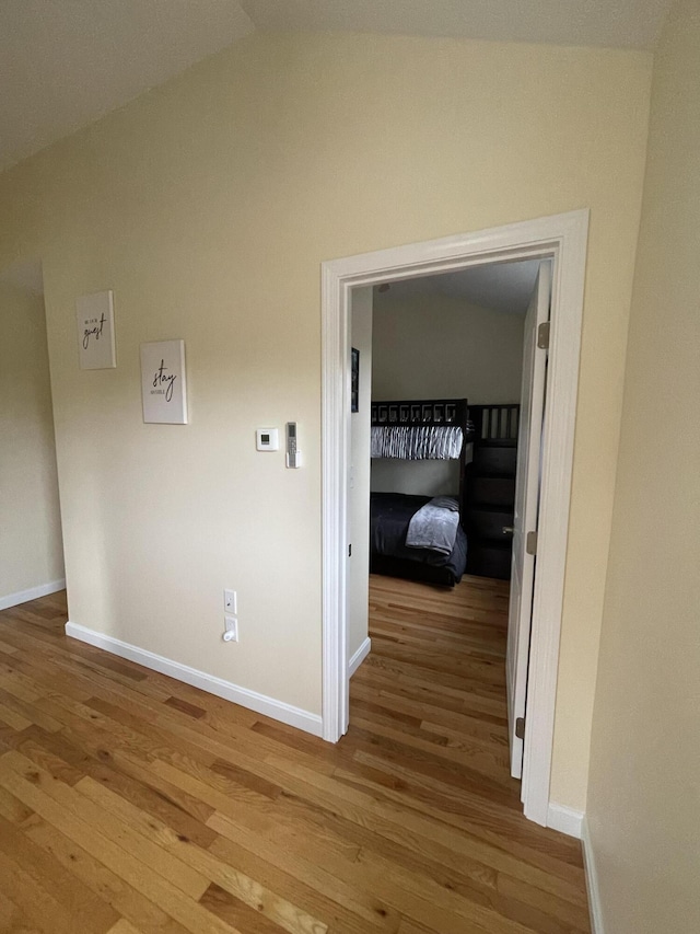 hall with light hardwood / wood-style flooring and vaulted ceiling