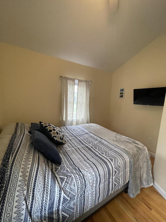 bedroom featuring hardwood / wood-style floors and vaulted ceiling